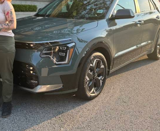 Customer standing beside their new green Kia Niro
