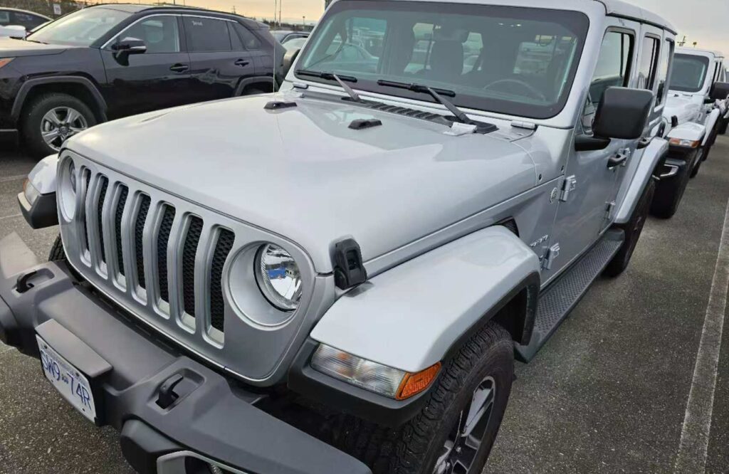 Silver 2024 Jeep Wrangler Unlimited parked in a dealership lot in British Columbia, Canada.