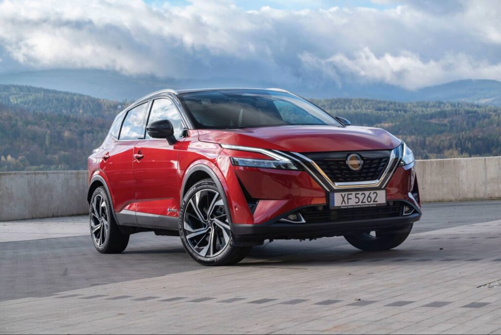Red Nissan SUV parked with mountain landscape in background