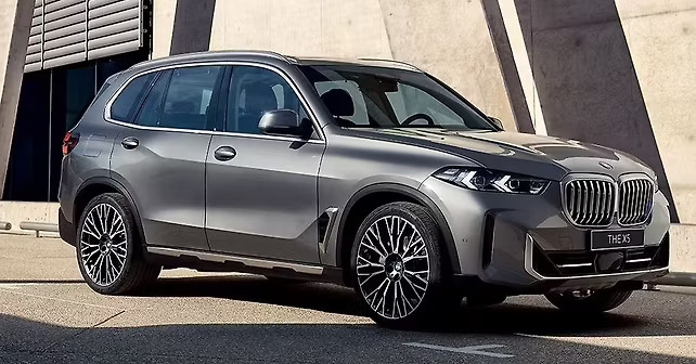 Luxury BMW X5 SUV parked outside a dealership building in daylight